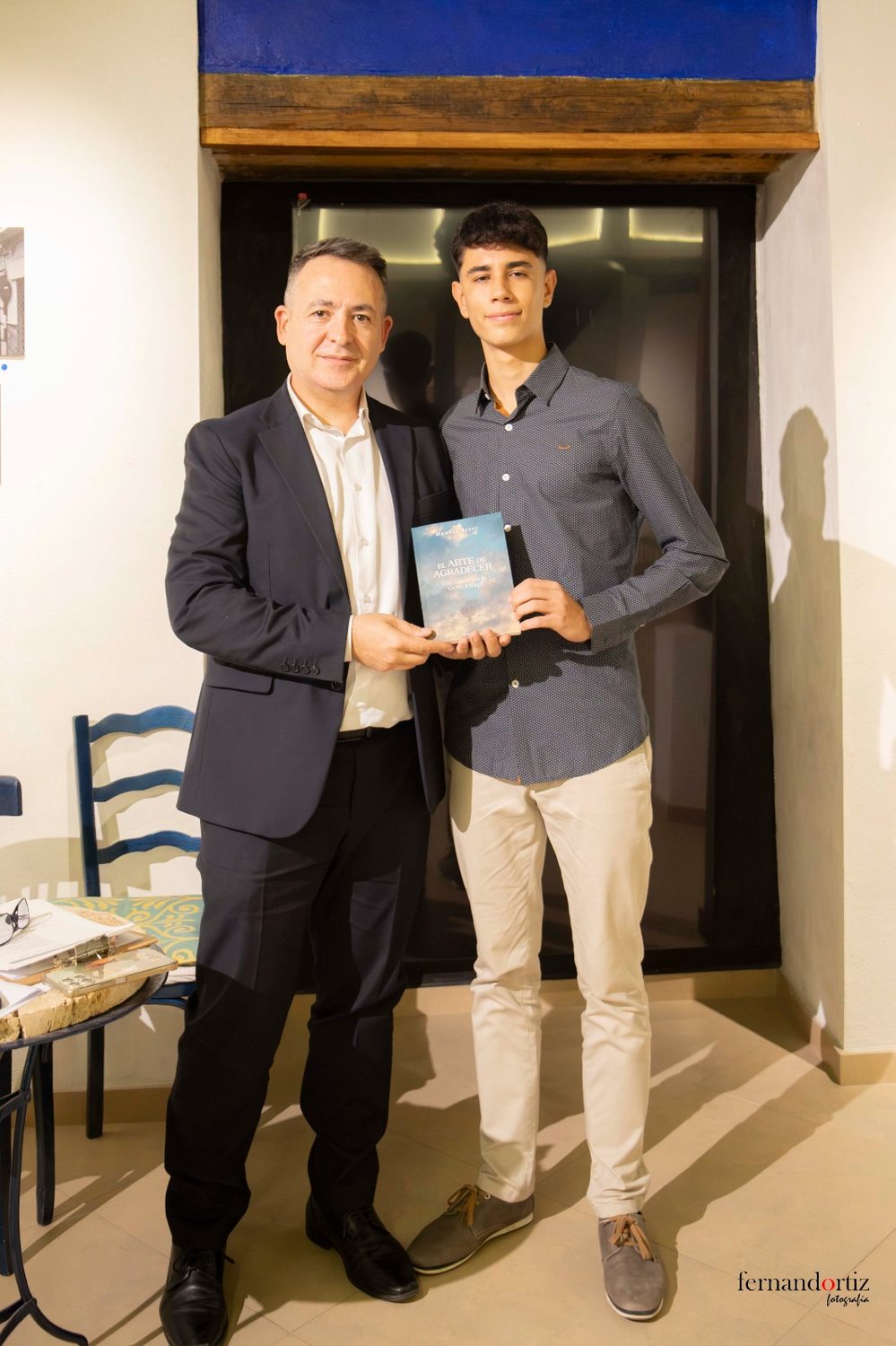 Manuel Reyes con un joven asistente, sosteniendo juntos un ejemplar de El arte de agradecer
