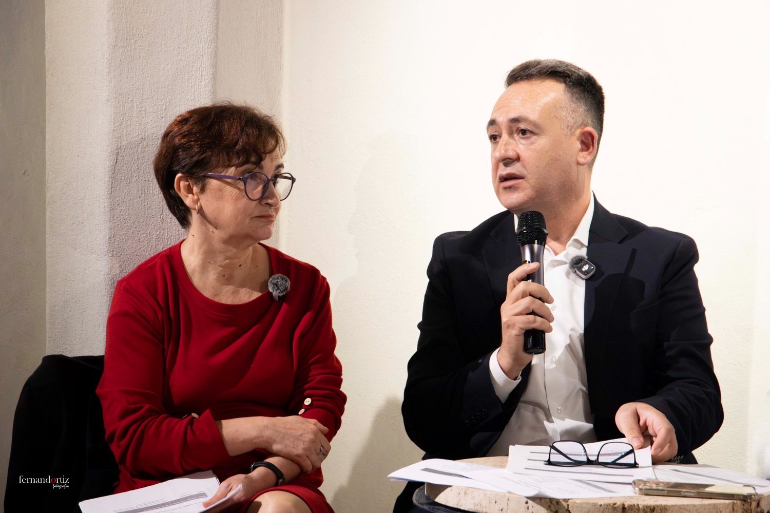Primer plano de dos intervinientes en la mesa de la presentación, uno de ellos hablando al micrófono