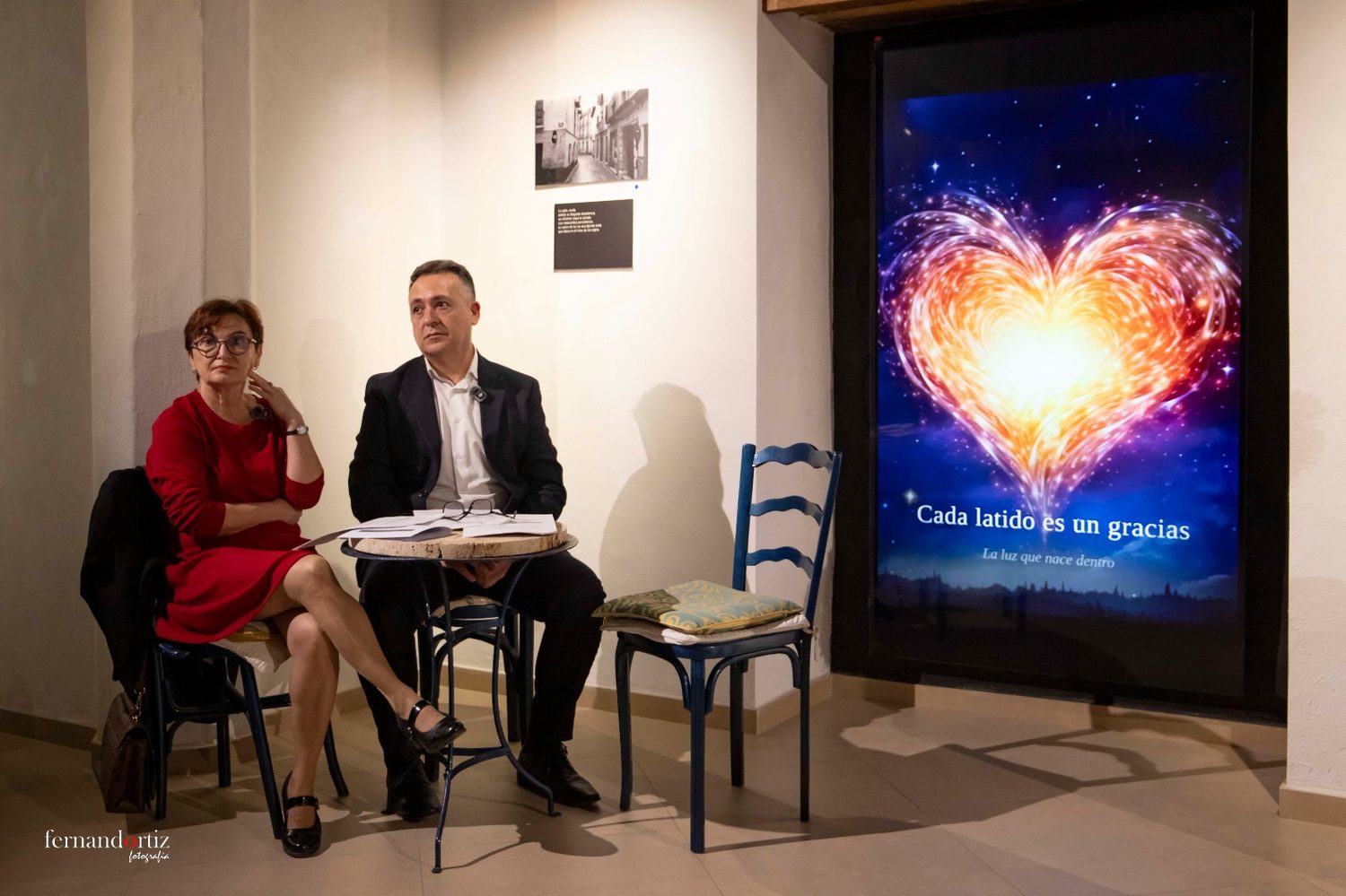 Dos intervinientes sentados junto a una pantalla con un corazón luminoso y la frase Cada latido es un gracias